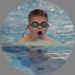 Child wearing swim goggles in the water